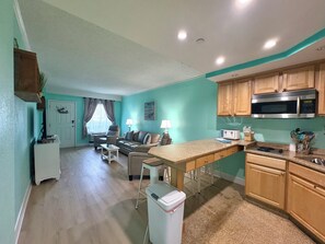 A modern kitchen with wooden cabinets, a microwave, and a stove. - Cozy Soundside Retreat at Villas of Hatteras Landing (Hatteras)