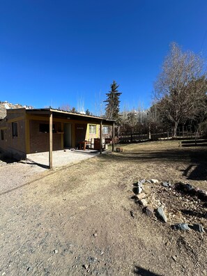 A single-story building with a covered porch, a small attached structure, and a fenced yard.