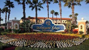 A Westgate Lakes Resort & Spa sign with palm trees and a flower bed. - Westgate Lake 2 Bed in Orlando close to Disney (Orlando)