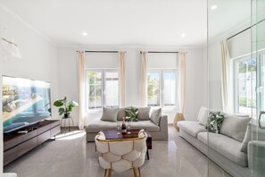 Uma sala de estar moderna com um sofá, uma mesa de jantar e uma televisão.