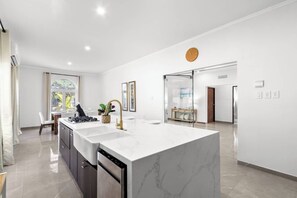 A modern kitchen with a large island, built-in appliances, and a view to the dining area. - New Lux 4 BR Private Villa & Walk to the Beach (Noord)