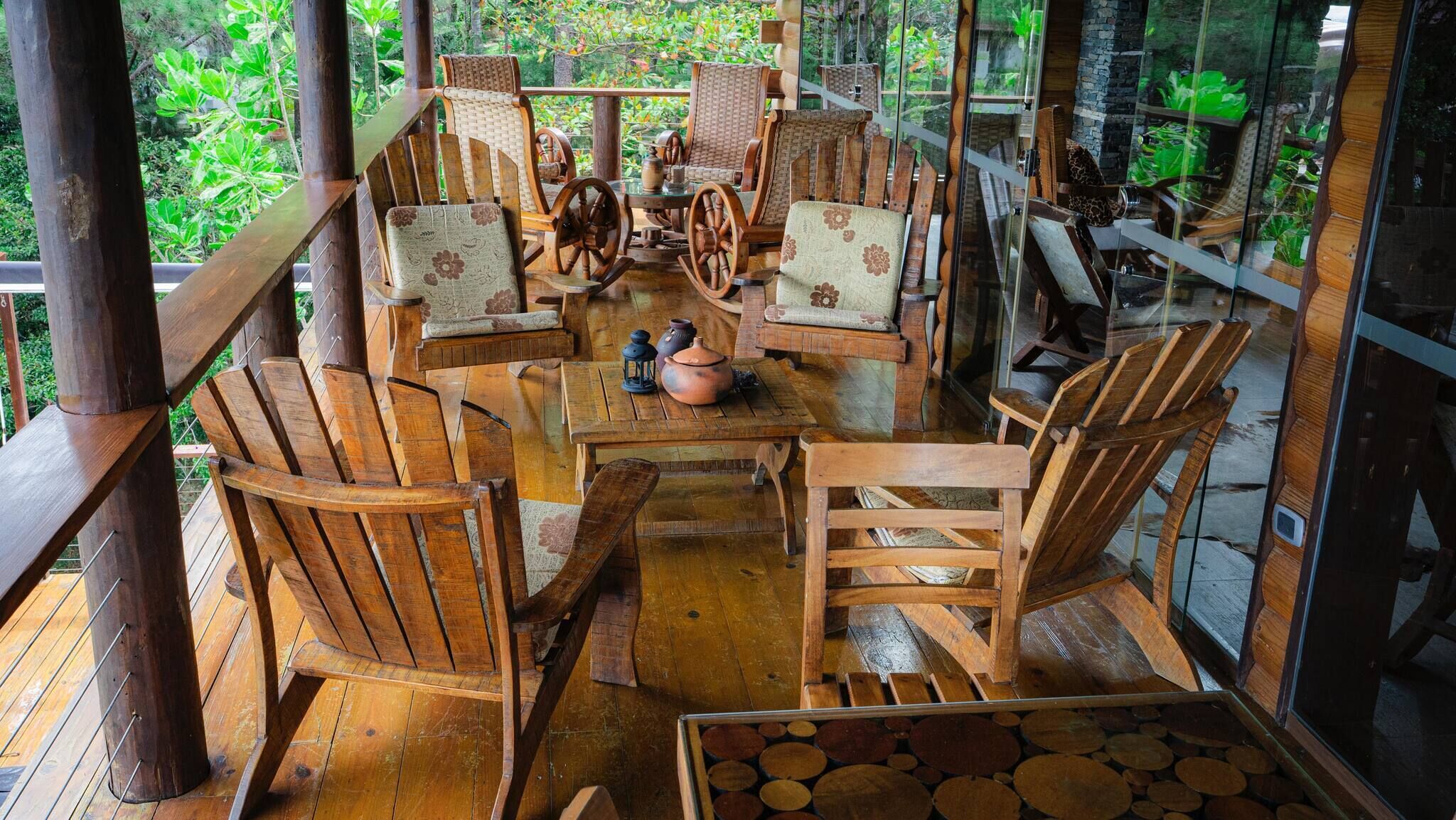 A wooden deck with a round table and chairs, surrounded by glass walls.