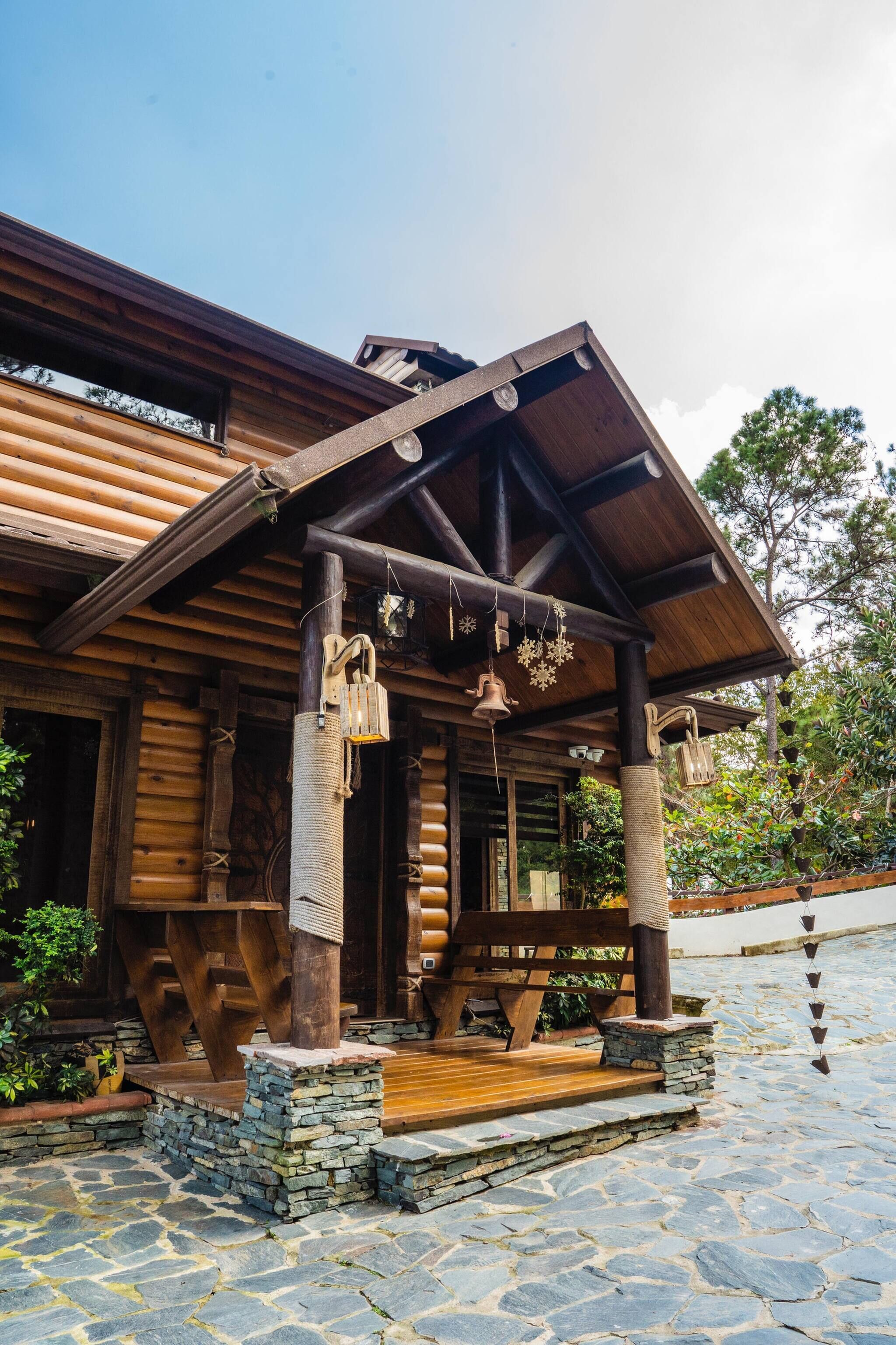 A wooden cabin with a porch, stone steps, and a wooden deck.