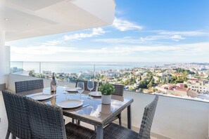 Ein Essbereich mit Tisch für vier Personen, mit Blick auf Stadt und Meer.
