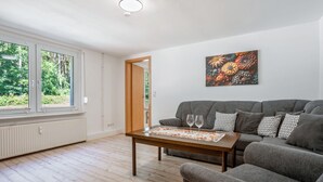 Een woonkamer met een grijze bank, een houten salontafel en een schilderij aan de muur.