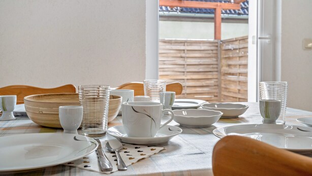 Een eettafel gedekt met borden, kommen, glazen en bestek.