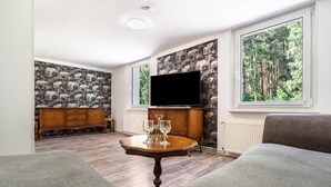 A living room with a television, a wooden cabinet, a table with glasses, and a sofa. - Holiday Apartment for 2 People (60 m²) in Wolgast OT Buddenhagen (Wolgast)