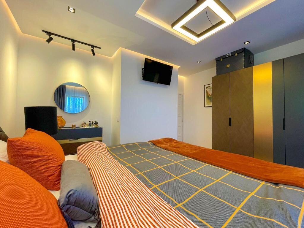 Un dormitorio moderno con cama, espejo, televisión y armario.