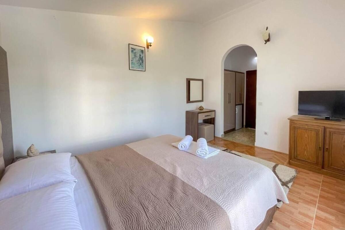 A hotel room with a bed, a television, a desk, and a bathroom visible through an archway.