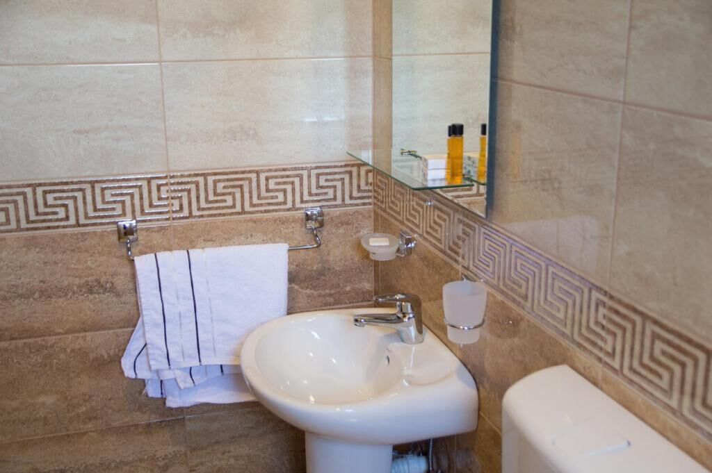 A bathroom with a white sink, a towel rack, a toilet, and a mirror.