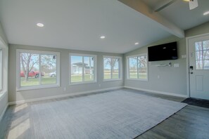 A spacious room with large windows, a flat-screen TV mounted on the wall, and a door with a doormat. - Truman Lake Country Home: Circle Drive for Boats/Trailers & Family Friendly (Clinton)