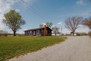 Ein Haus mit Kiesweg, rotem Dach und einem großen Baum im Vordergrund.