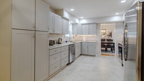 A modern kitchen with white cabinets, stainless steel appliances, and a dining area with a bench.