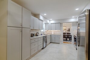 Una cocina moderna con armarios blancos, electrodomésticos de acero inoxidable y una zona de comedor con banco.