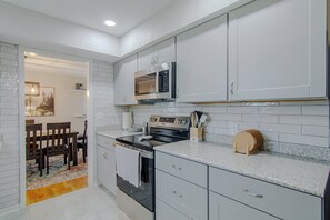 A kitchen with white cabinets, a microwave, a stove, and a dining area with chairs and a table. - Truman Lake Country Home: Circle Drive for Boats/Trailers & Family Friendly (Clinton)