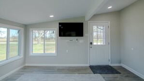 A room with a large window, a door, and a mounted TV.