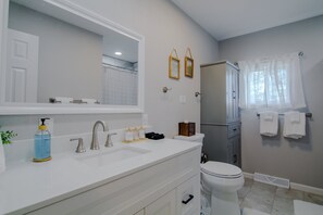 Ein Badezimmer mit weißem Waschbecken, Spiegel, Toilette und Handtuchhalter.