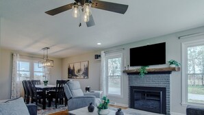 A living room with a fireplace, a dining area, and a TV mounted on the wall.