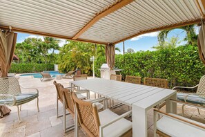 Eine Außenpatio mit überdachter Essgegend, Liegestühlen und einem Pool.