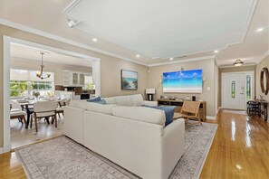Ein geräumiger Wohnbereich mit einer großen Couch, einem Esstisch und einer Küche im Hintergrund.