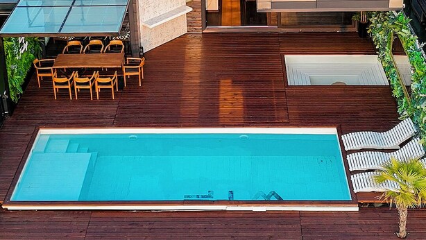 Ett modernt hus med en swimmingpool, utemöbler och utsikt över den omgivande naturen.