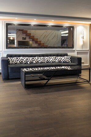 Ein modernes Wohnzimmer mit einer Couch, einem gestreiften Hocker und einem Glastisch.