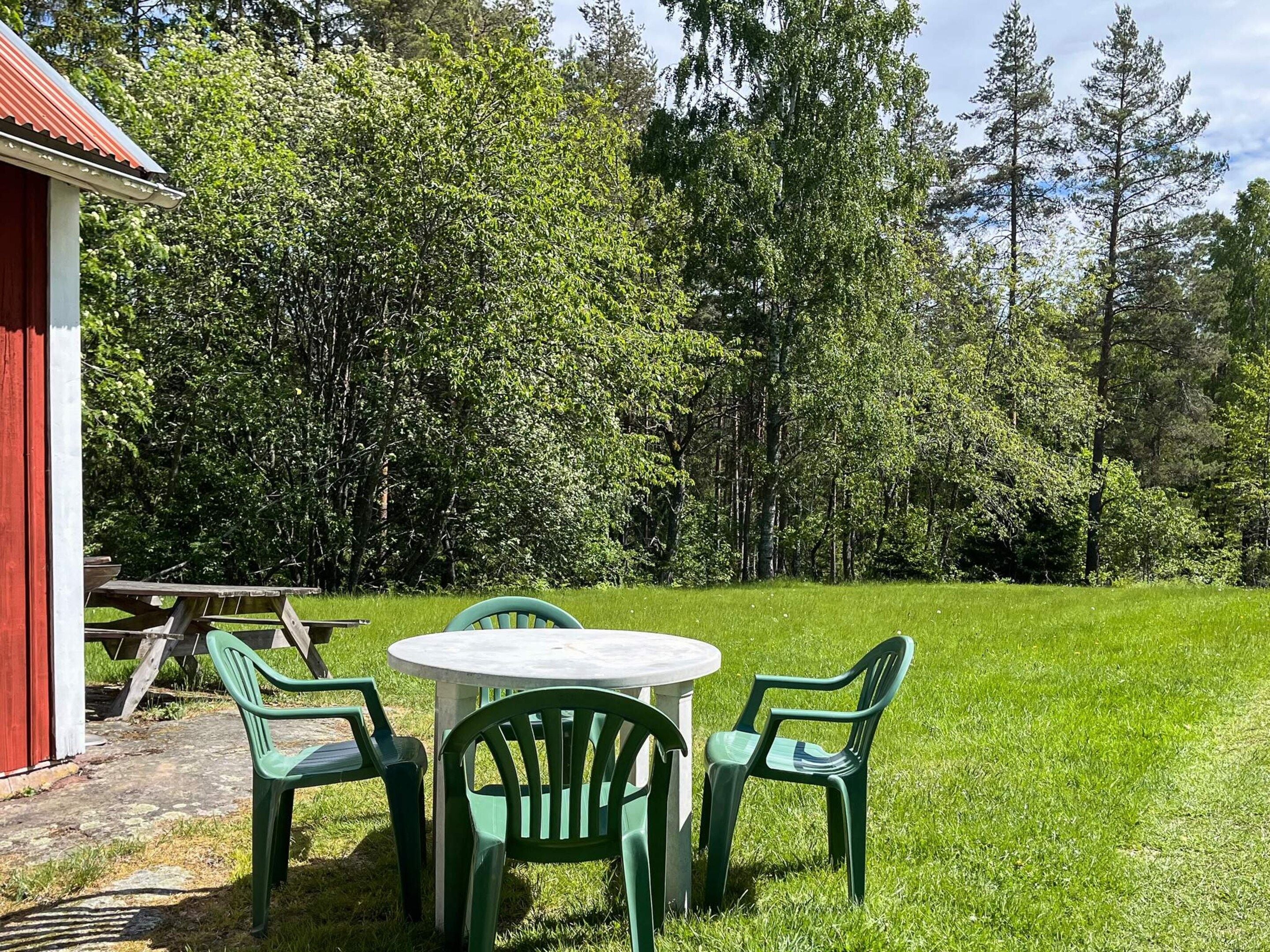 A picnic table with four chairs and a red building in the background.