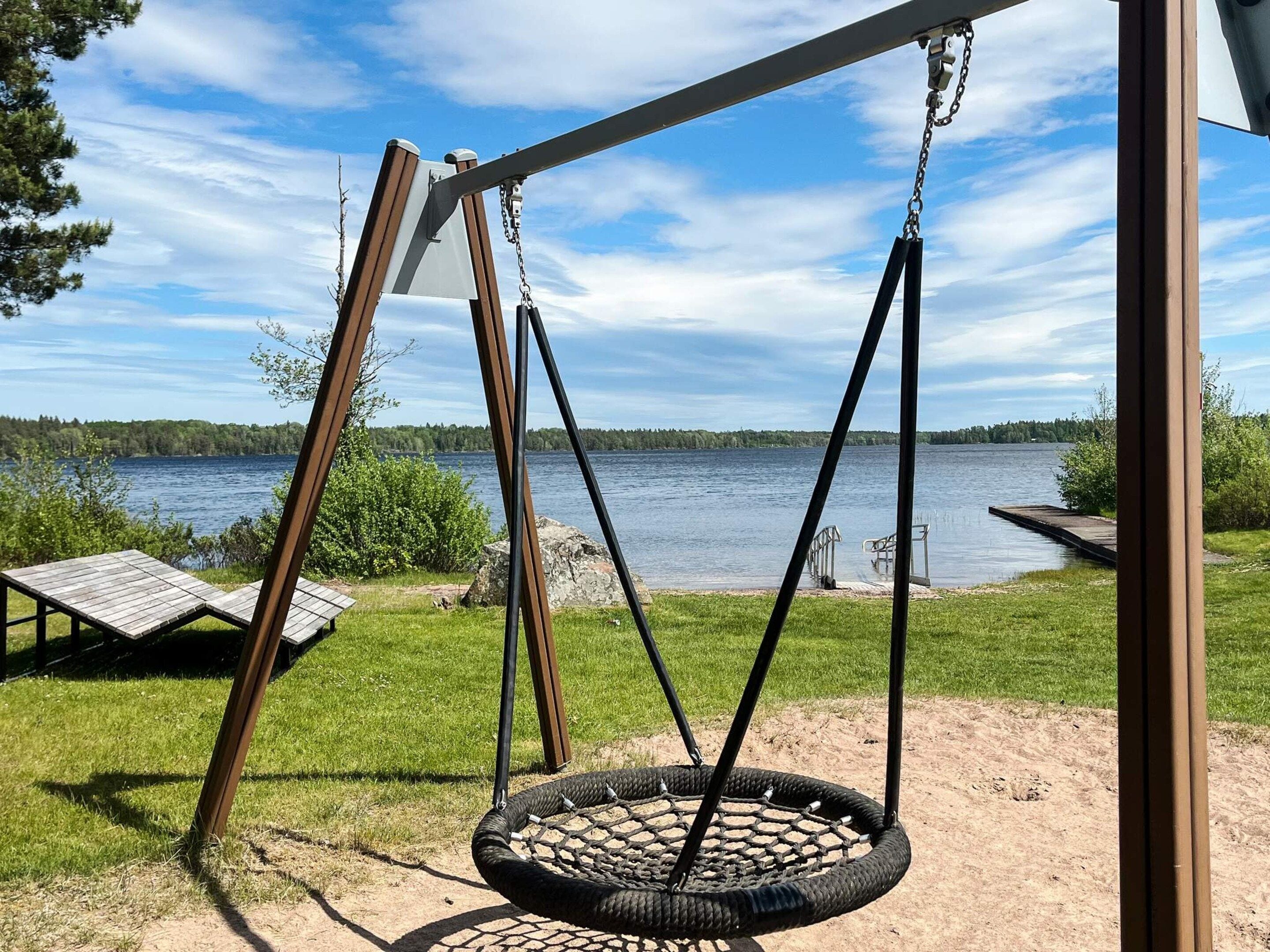 Une balançoire avec un pneu servant de siège, un banc en bois et une vue sur un lac.