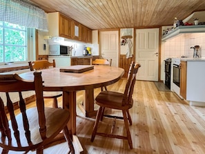A kitchen with wooden cabinets, a round dining table, and chairs. - 5 Person Holiday Home in Kristdala (Kristdala)