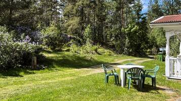 A grassy outdoor area with a white gazebo, green plastic chairs, and a table.
