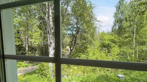 A window view of a forested area with a path, a metal railing, and a water container on the ground. - 5 Person Holiday Home in Kristdala (Kristdala)