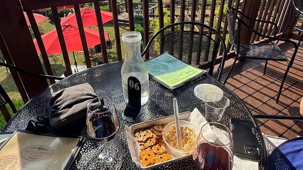 A round metal table with a bottle, glasses, a plate, and a menu on a balcony overlooking a scenic landscape. - Mountain view - Marvelous campground in Columbus perfect for your next adventure (Columbus)