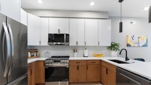 Una cocina moderna con electrodomésticos de acero inoxidable, armarios de madera y una encimera blanca.