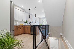 Una cocina moderna con armarios blancos, un refrigerador de acero inoxidable y una barandilla negra.