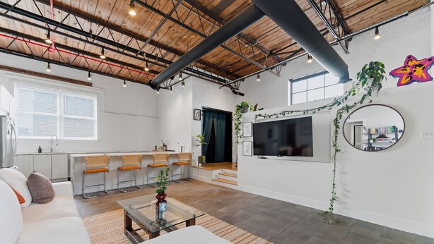 A modern living room with a sofa, coffee table, and a TV mounted on the wall. - Cozy industrial loft with rooftop close to FIFA (Atlanta)