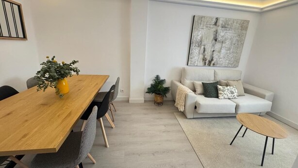Una sala moderna con una mesa de comedor de madera, un sofá y una mesa baja.