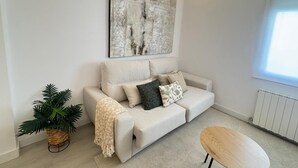 Una sala de estar moderna con un sofá, una mesa de centro, una planta en maceta y un cuadro abstracto grande en la pared.
