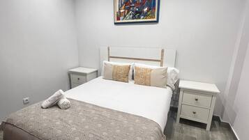 Een slaapkamer met een bed, twee nachtkastjes, een schilderij aan de muur en een bed met een patroon.