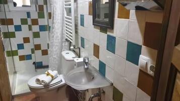 Un bagno con WC, lavandino e zona doccia, rivestito di piastrelle multicolore.
