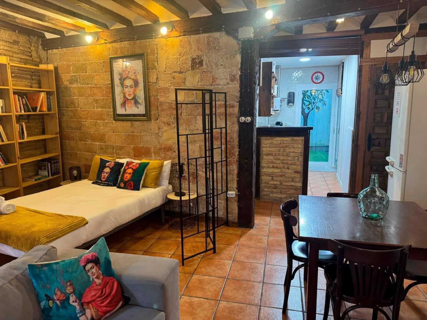 Una habitación acogedora con cama, sofá, mesa de comedor y estantería.