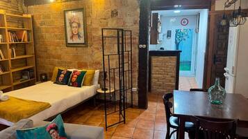 Una habitación acogedora con cama, sofá, mesa de comedor y estantería.