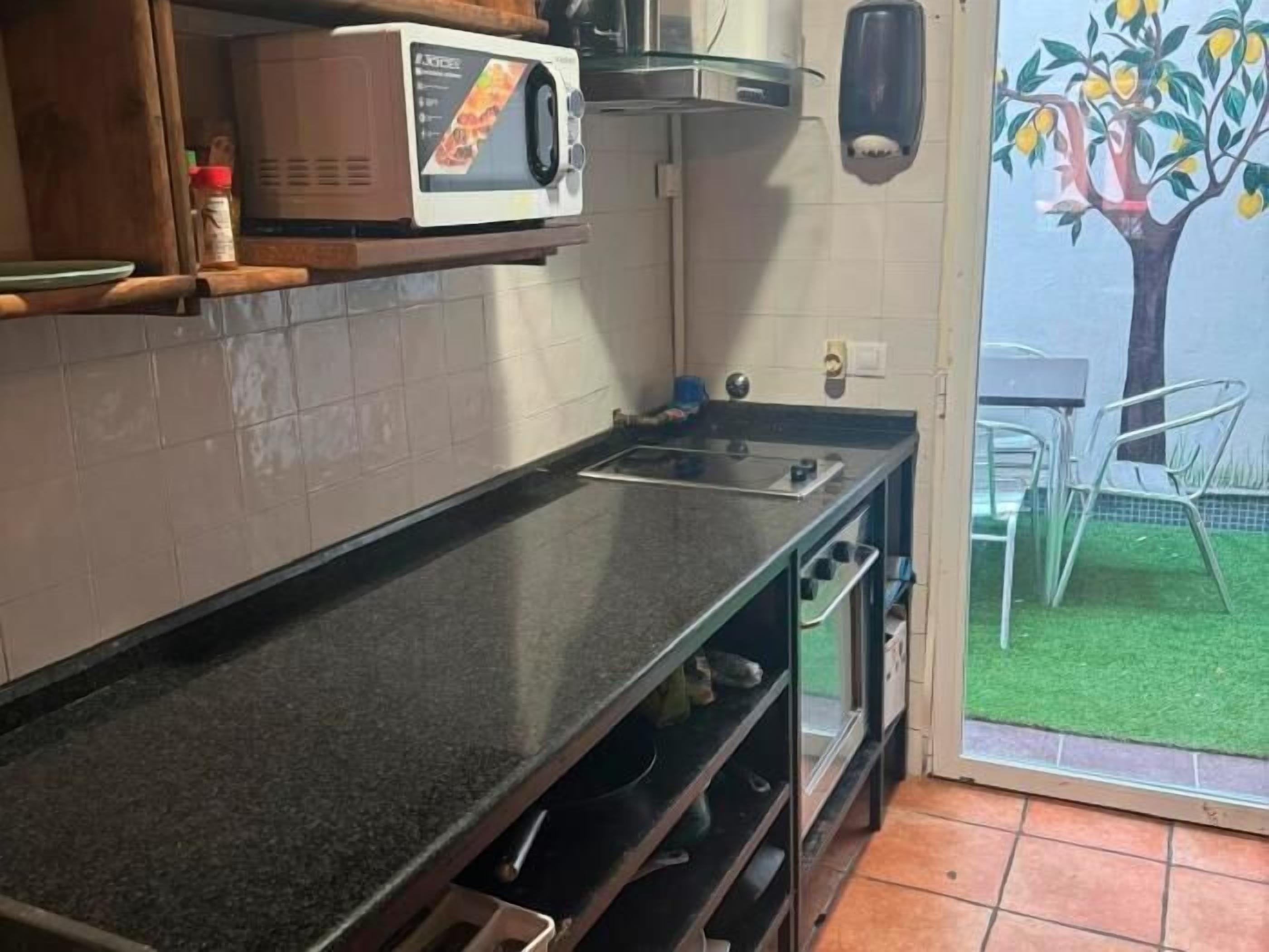 Una cocina con microondas, estufa y vistas a un jardín a través de un ventanal.