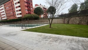 Une cour avec une piscine, une pelouse et un bâtiment doté de plusieurs balcons.