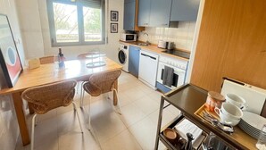 Une cuisine compacte comprenant un coin repas, un lave-linge et un four à micro-ondes.