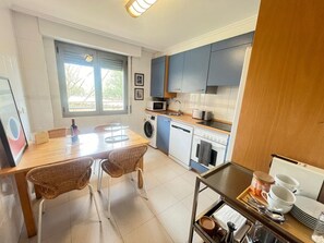 Een kleine keuken met een eethoek, een wasmachine en een magnetron.