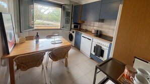 Une cuisine compacte comprenant un coin repas, un lave-linge et un four à micro-ondes.