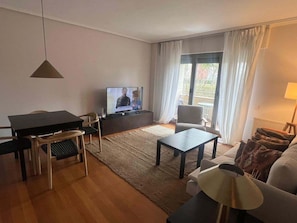 Una sala de estar con televisor, mesa de comedor, sofá y una silla.