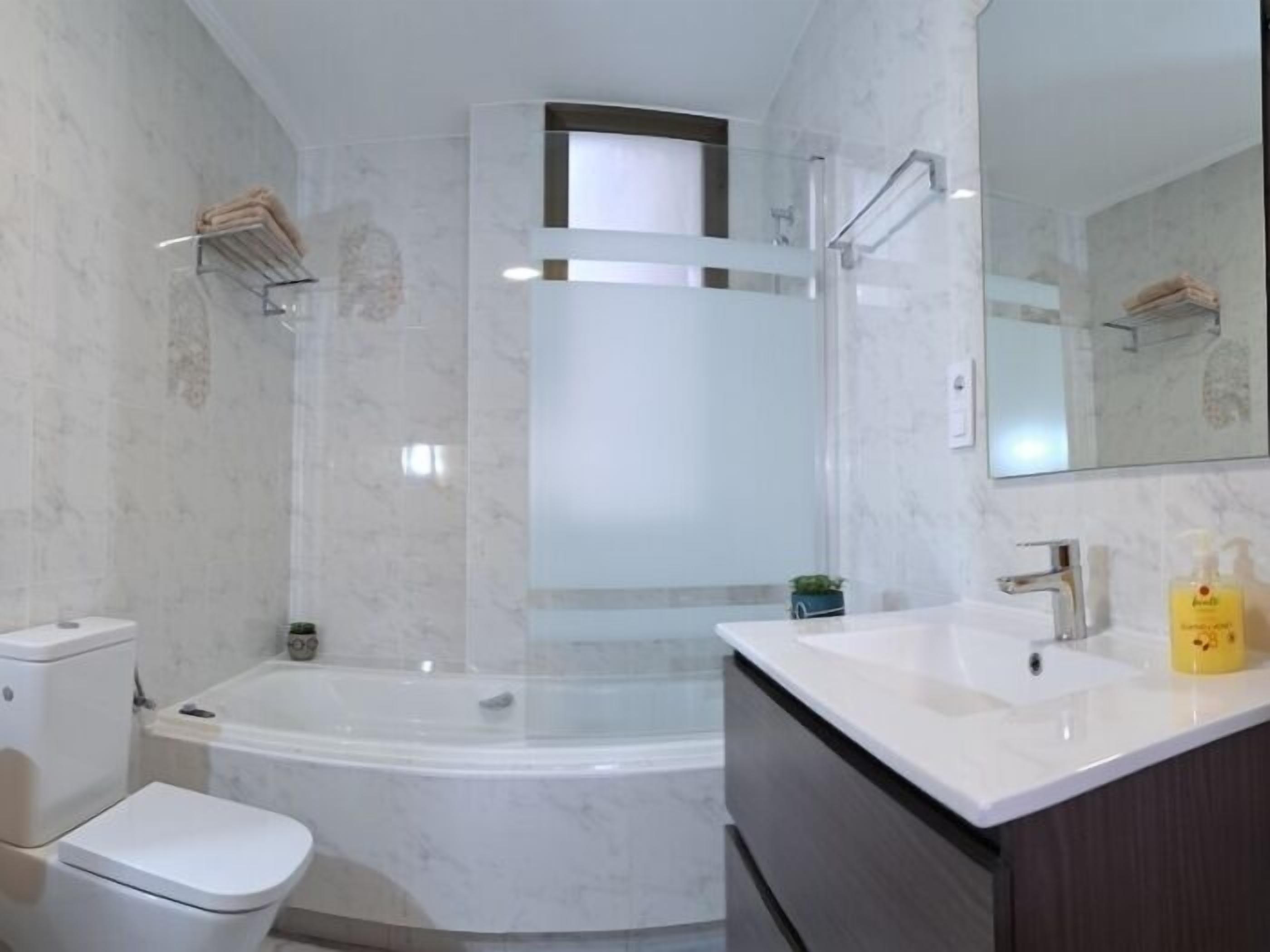 Un baño con bañera, inodoro, lavamanos y espejo.