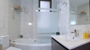 Un baño con bañera, inodoro, lavamanos y espejo.