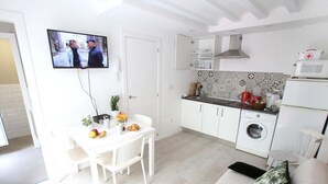 En kompakt opholdsstue med spiseplads, tekøkken og sofa.